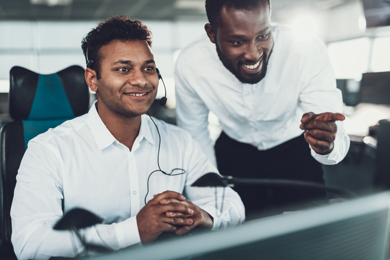 Two employees smiling and looking at computer.