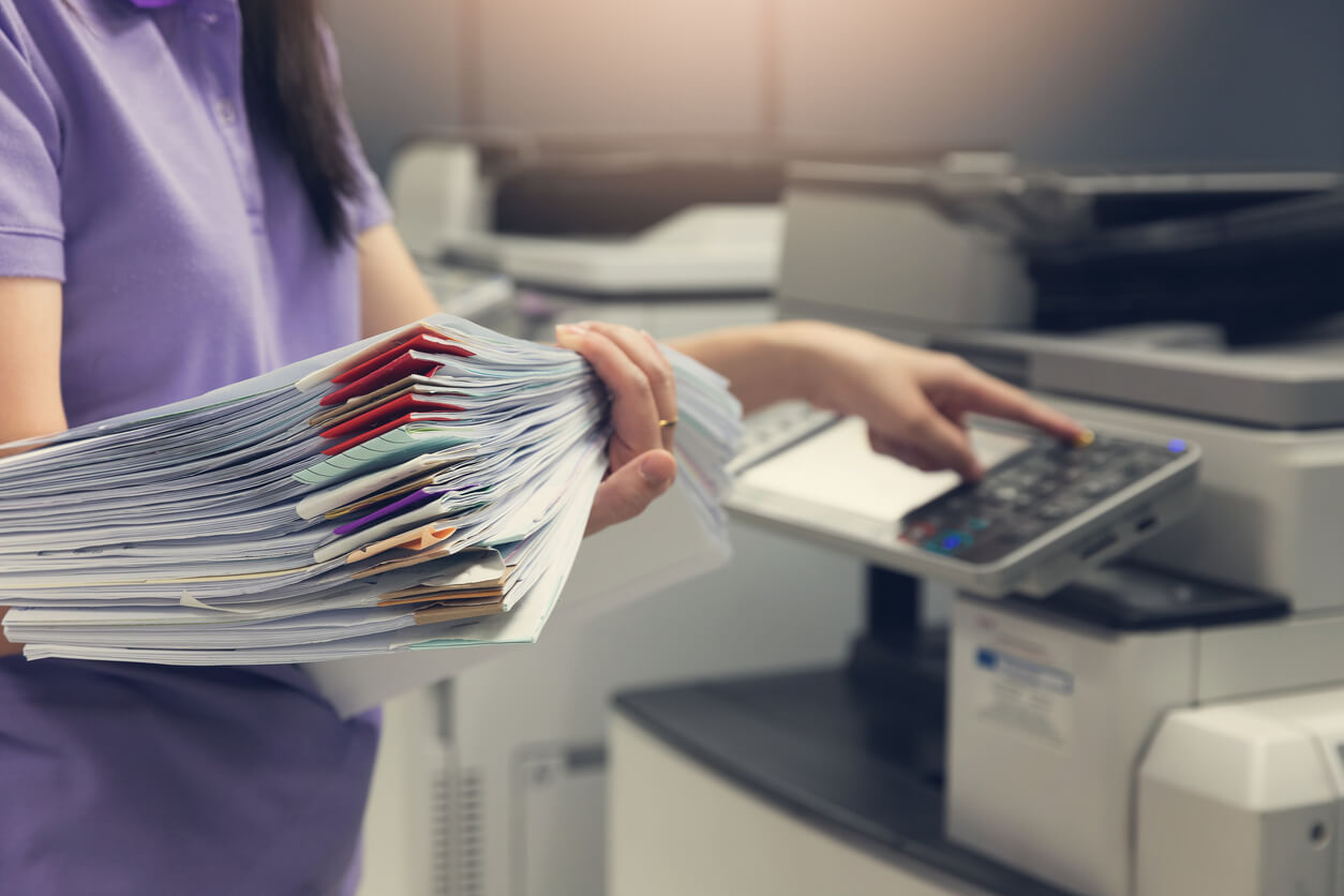 Employee making photo copies of confidential documents with color coded tabs.
