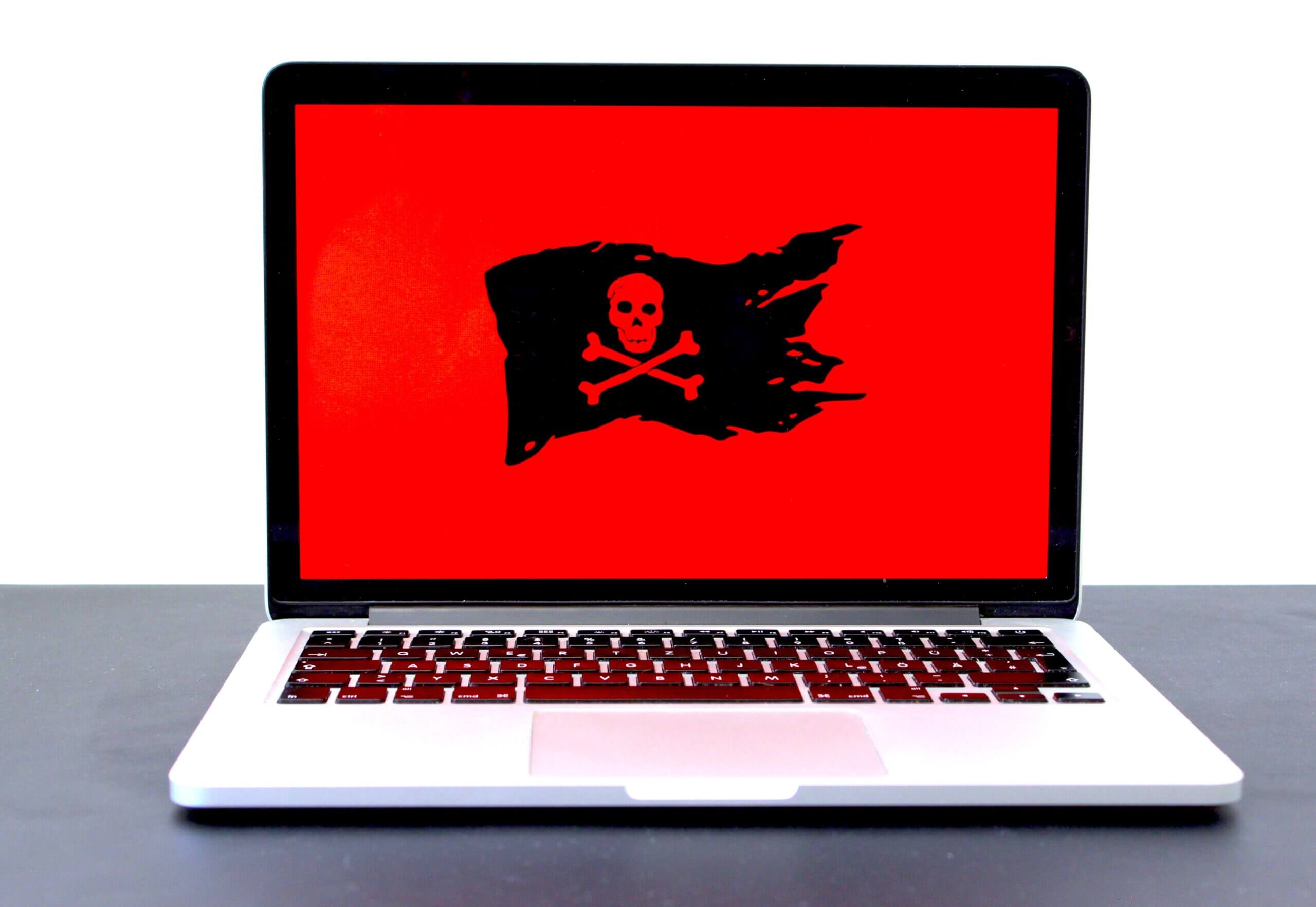 Laptop with malware and cybersecurity loaded with red background.