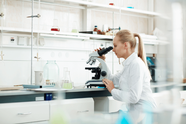 Woman scientist working in a lab and looking into a microscope.