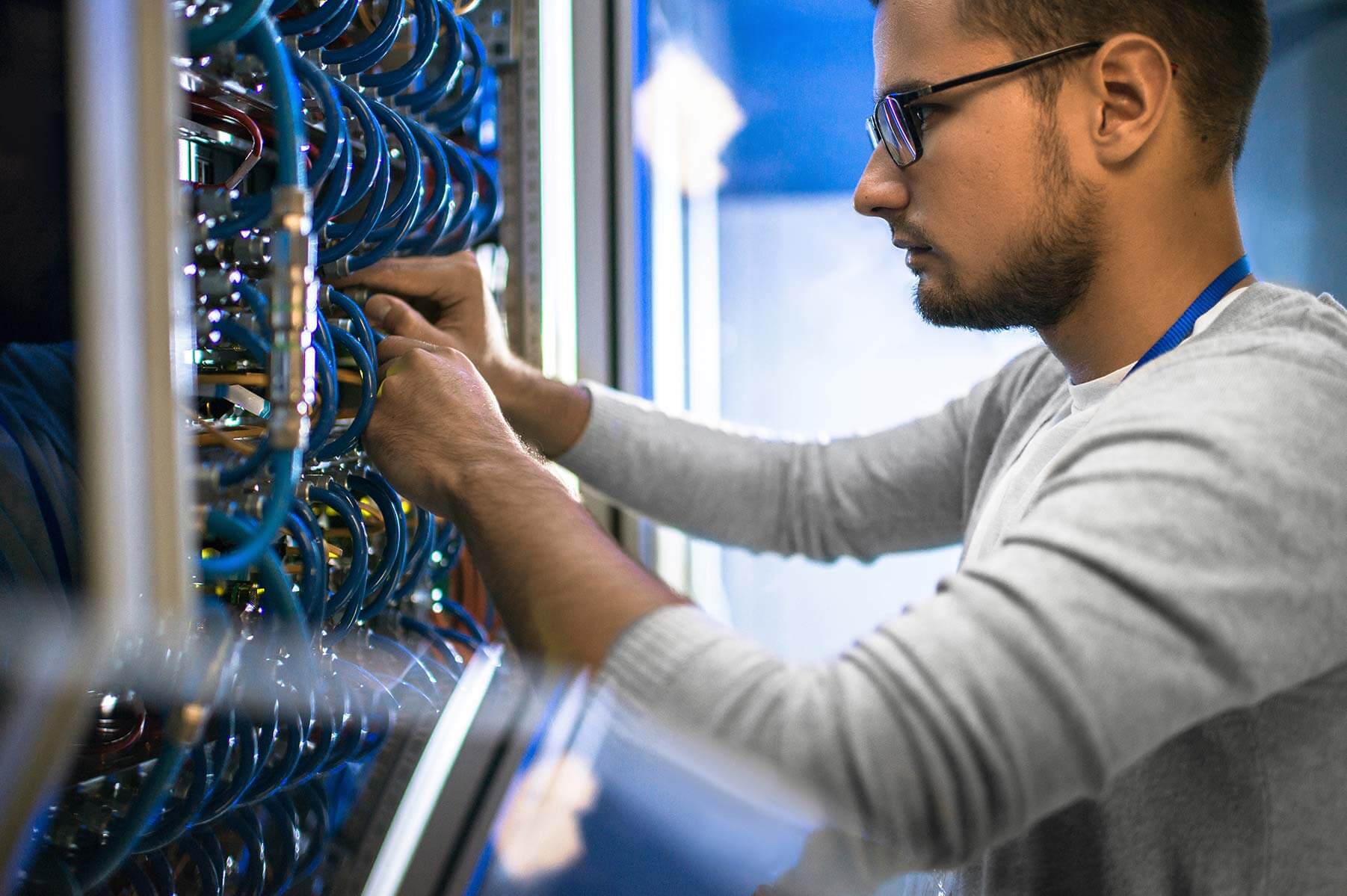IT employee performing wiring maintenance in an IT closet.